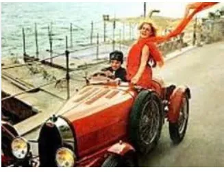A woman with a long red scarf riding in a vintage red open car