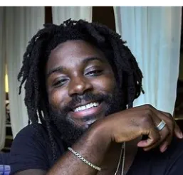 Jason Reynolds smiling, his chin resting on his hand