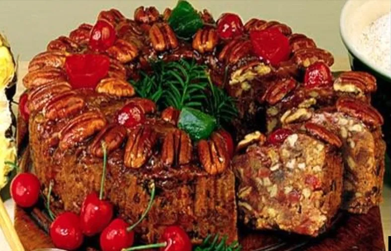 A fruitcake topped with pecans and candied cherries